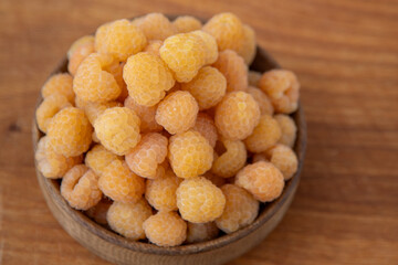 Yellow raspberries in a wooden bowl on the table. Summer berries background. Vitamin food, berry harvest. Healthy nutrition.