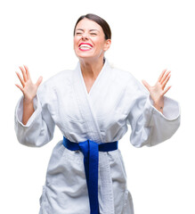 Young beautiful woman wearing karate kimono uniform over isolated background celebrating mad and...