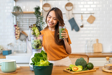 Portrait of beauty healthy asian woman making green vegetables detox cleanse and green fruit smoothie with blender.young girl drinking glass of smoothie, fiber, chlorophyll in kitchen.Diet, healthy - Powered by Adobe