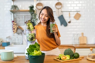 Tuinposter Portrait of beauty healthy asian woman making green vegetables detox cleanse and green fruit smoothie with blender.young girl drinking glass of smoothie, fiber, chlorophyll in kitchen.Diet, healthy © Art_Photo