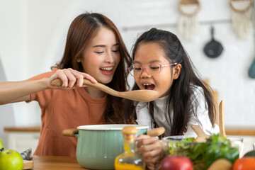 Portrait of enjoy happy love asian family mother with little asian girl daughter child help cooking...