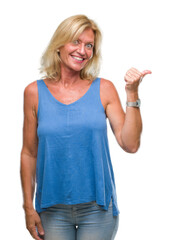 Middle age blonde woman over isolated background smiling with happy face looking and pointing to the side with thumb up.