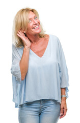 Fototapeta premium Middle age blonde business woman over isolated background smiling with hand over ear listening an hearing to rumor or gossip. Deafness concept.