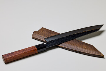 Professional kitchen knife next to a wooden sheath