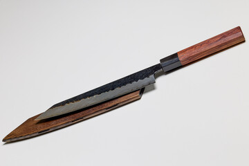 Naklejka premium Professional kitchen knife next to a wooden sheath