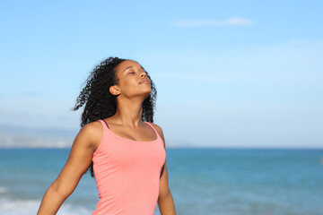 Black casual woman breathing fresh air on the beach