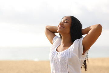 Joyful black woman breathing on the beach - obrazy, fototapety, plakaty
