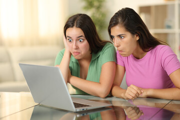 Perplexed friends checking laptop at home