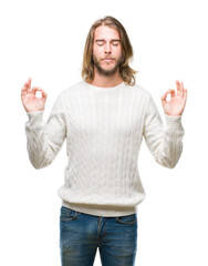 Young handsome man with long hair wearing winter sweater over isolated background relax and smiling with eyes closed doing meditation gesture with fingers. Yoga concept.