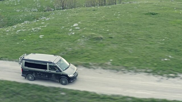 Drone footage of a van traveling through landscape on gravel road. Bosnia