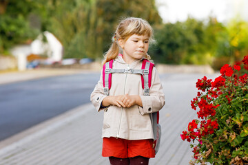 Fototapeta premium Cute little preschool girl going to playschool. Healthy toddler child walking to nursery school and kindergarten. Happy child with backpack on the city street, outdoors.