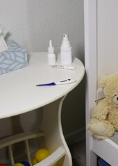 Flue medicine bottles and a thermometer on white table in baby room