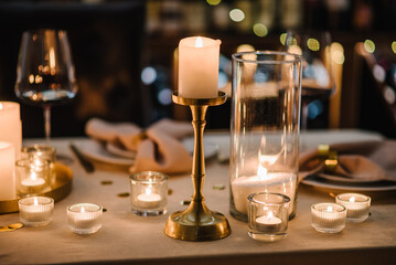 Luxury candle light date in restaurant. Bokeh, garlands, bouquet flowers. Romantic dinner setup at night. Table set for couple, Valentine's Day evening, burning candles for surprise marriage proposal. - obrazy, fototapety, plakaty