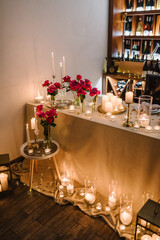 Decoration flowers, burning candles, details closeup. Luxury romantic date. Location for a surprise proposal at night. Table setting in restaurant for event. Candlelight for couple on Valentines day.
