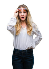 Young beautiful blonde woman wearing sunglasses over isolated background afraid and shocked with surprise expression, fear and excited face.