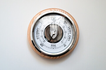 Large, analog weather pressure barometer showing both air pressure and associated weather conditions. The pressure chamber coil can be seen on the centre.