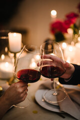 Couple in love drinking wine. Cheers. Romantic date by candlelight at night. Hands man and woman...