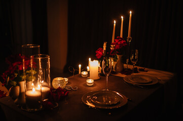 Candlelight date in restaurant. Champagne glasses, bouquet flowers. Romantic dinner setup at night. Table setting for couple, Valentine's Day evening, burning candles for surprise marriage proposal.