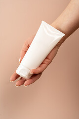 Woman holding white tube of face care or body cream, body care concept