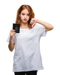 Young beautiful woman holding passport of canada over isolated background with angry face, negative sign showing dislike with thumbs down, rejection concept