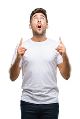 Young handsome man over isolated background amazed and surprised looking up and pointing with fingers and raised arms.