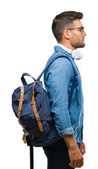 Young handsome tourist man wearing headphones and backpack over isolated background looking to...