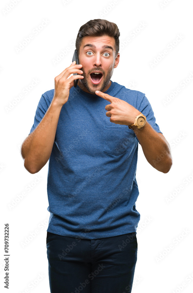 Wall mural Young handsome man talking on smartphone over isolated background very happy pointing with hand and finger