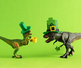 Two green dinosaurs in green hats with beer and clover leaf celebrating St. Patrick's day. Unusual...