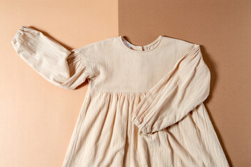 Top view flat lay linen kids dress on beige and brown background. Eco friendly kids fashion concept.
