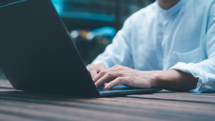 a businessman or freelancer using computer laptop sitting on table outside working on business or...