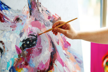 The hand with a brush draws a painting wih horse