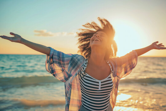 Joyful young woman with arms outstretched soaking up the sunshine on a serene beach, symbolizing freedom, happiness, or summer vacation