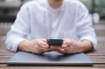 a businessman or freelancer using computer laptop and smartphone sitting on table outside working on business or internet online marketing