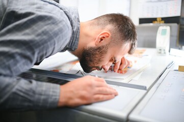 Graphic engineer or worker checking imprint quality in modern print shop