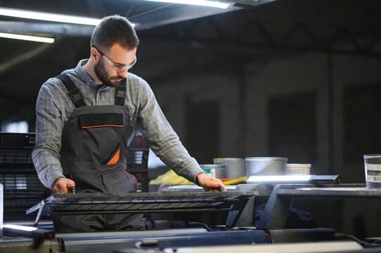 Print worker trying to fix the problem on computer to plate machine in printing shop