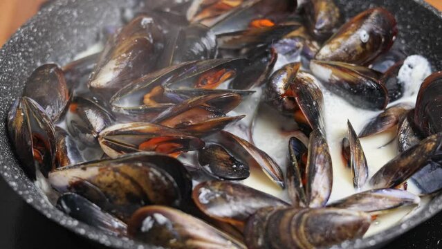 Close-up of Mediterranean mussels prepared with cream sauce. Slow rotation of mussels opened in hot pan.