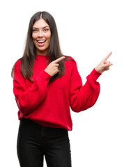 Young beautiful hispanic wearing red sweater smiling and looking at the camera pointing with two...