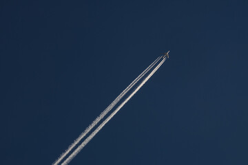 Flying airplane on the blue sky with white tale 