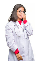 Young arab doctor woman over isolated background smelling something stinky and disgusting, intolerable smell, holding breath with fingers on nose. Bad smells concept.
