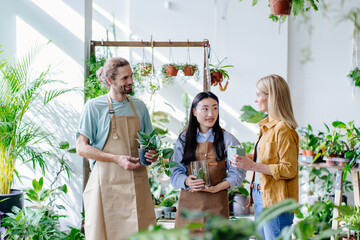 Obraz premium Welcoming two Florists owner, shop interior, seller, customer, potted plants. Floral business concept.