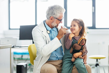Portrait of a pediatrician with a little patient sitting on his knee. Friendly relationship between...