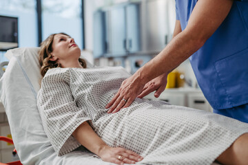 Doctor palpating woman's abdomen, using hands and steady pressure.