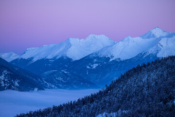 sommets d'une chaîne de montagne enneigée au crépuscule avec un beau ciel rose