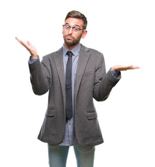 Young handsome business man over isolated background clueless and confused expression with arms and hands raised. Doubt concept.