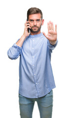 Young handsome man speaking on the phone over isolated background with open hand doing stop sign with serious and confident expression, defense gesture