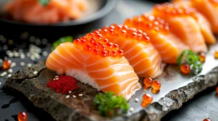 Rolgordijnen Raw salmon sashimi on rice with shiny salmon roe. Salmon sushi pieces on stone plate garnished with red caviar, close-up. Nigiri sushi with succulent salmon and roe. © Alina