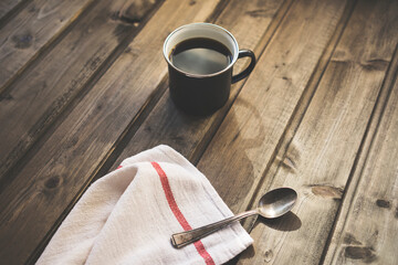 Black coffee in enamel mug on wooden background