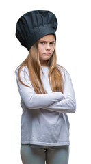 Young beautiful girl wearing chef hat uniform over isolated background skeptic and nervous, disapproving expression on face with crossed arms. Negative person.