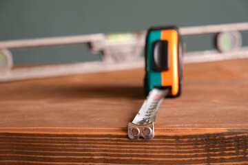 Hand tools for building and construction, vintage spirit level or bubble level and tape measure on a wooden background