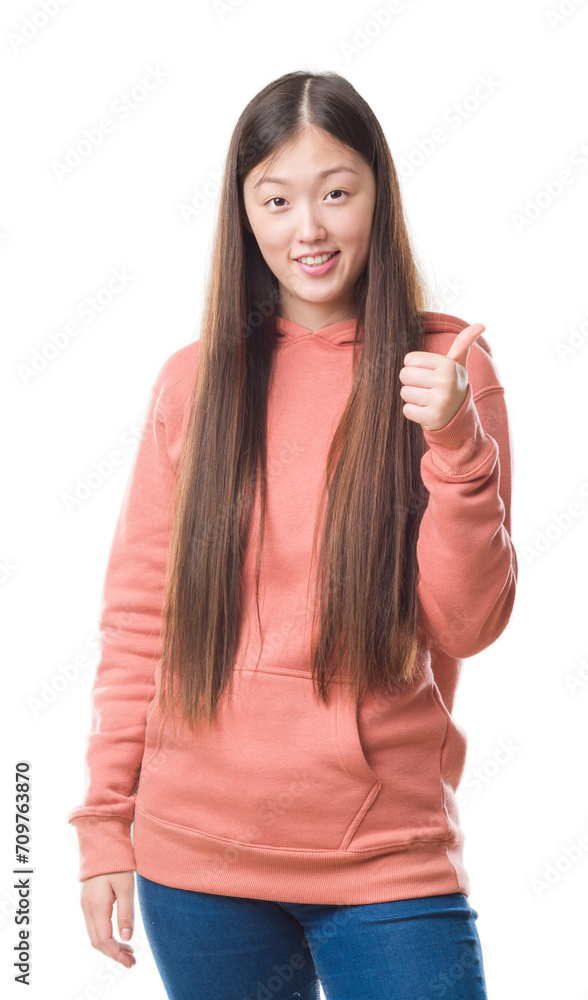 Wall mural young chinese woman over isolated background wearing sport sweathshirt doing happy thumbs up gesture